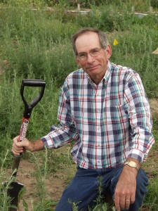 Jim Story kneeling in field with shovel in hand